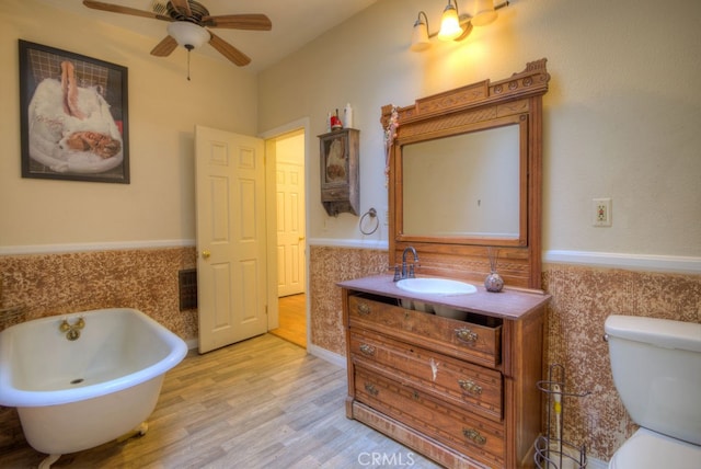 bathroom featuring toilet, ceiling fan, hardwood / wood-style flooring, vanity, and a bathtub