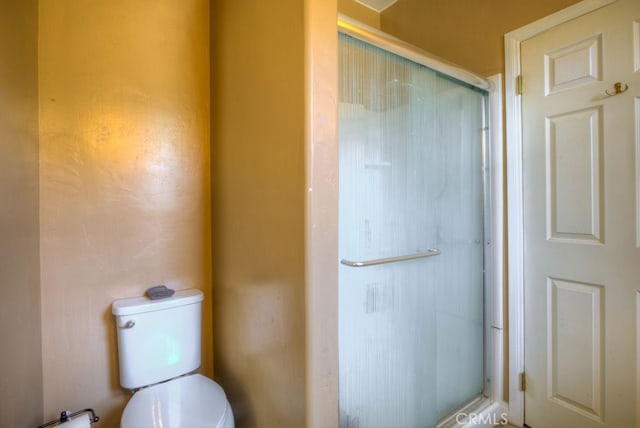 bathroom with a shower with door and toilet