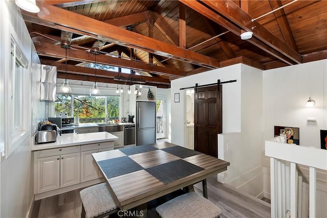 interior space with a barn door, wood ceiling, vaulted ceiling with beams, and light hardwood / wood-style flooring