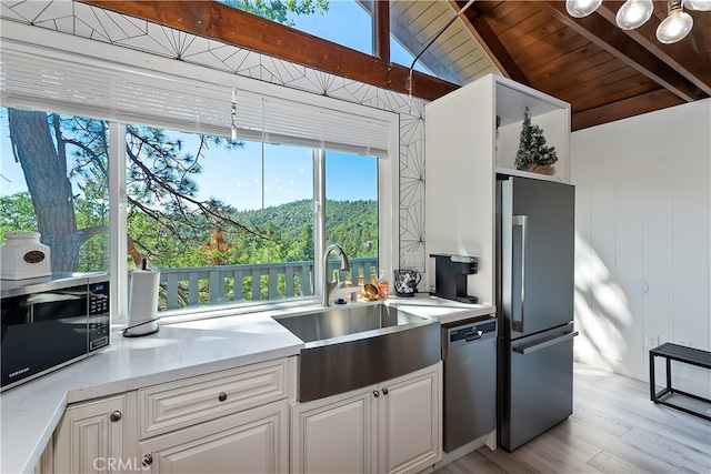 kitchen featuring light hardwood / wood-style floors, vaulted ceiling with beams, wood ceiling, appliances with stainless steel finishes, and white cabinets