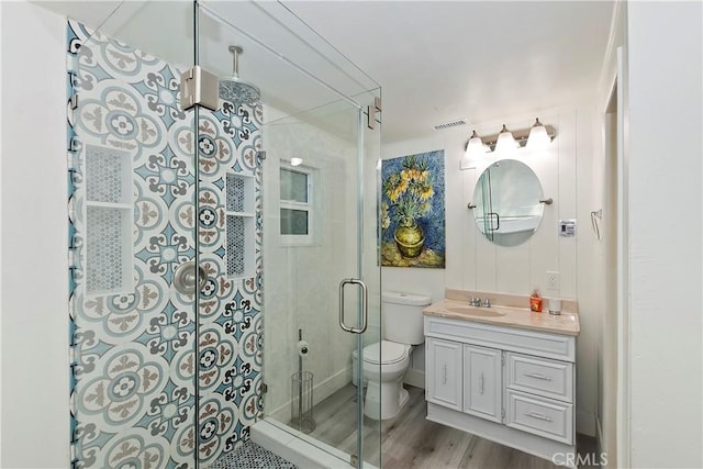 bathroom featuring toilet, vanity, hardwood / wood-style floors, and walk in shower