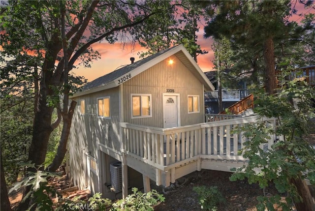 back house at dusk featuring a wooden deck