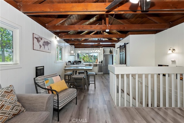 living area with lofted ceiling with beams, a barn door, wooden ceiling, light wood-type flooring, and an inviting chandelier