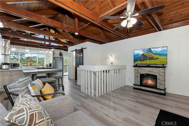 living room with a barn door, wood ceiling, ceiling fan, and light hardwood / wood-style flooring