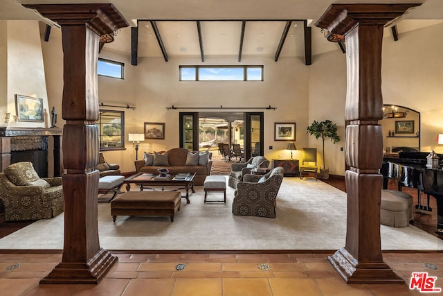 tiled living room featuring beam ceiling, ornate columns, and high vaulted ceiling