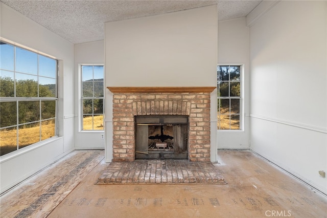 unfurnished living room featuring a brick fireplace, lofted ceiling, and a textured ceiling