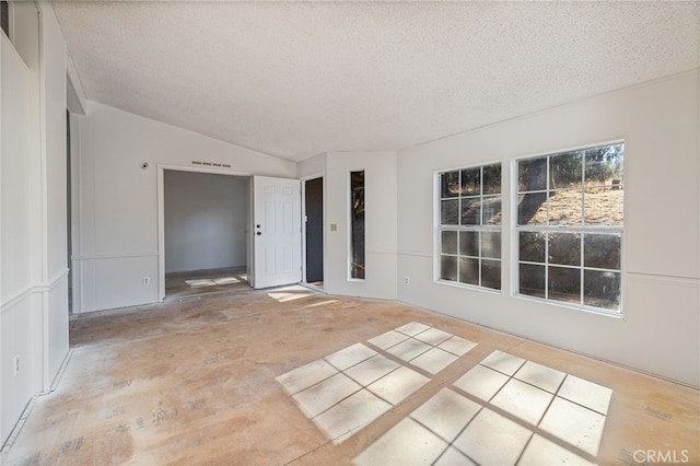 empty room with vaulted ceiling and a textured ceiling