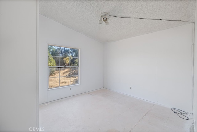 unfurnished room with lofted ceiling and a textured ceiling