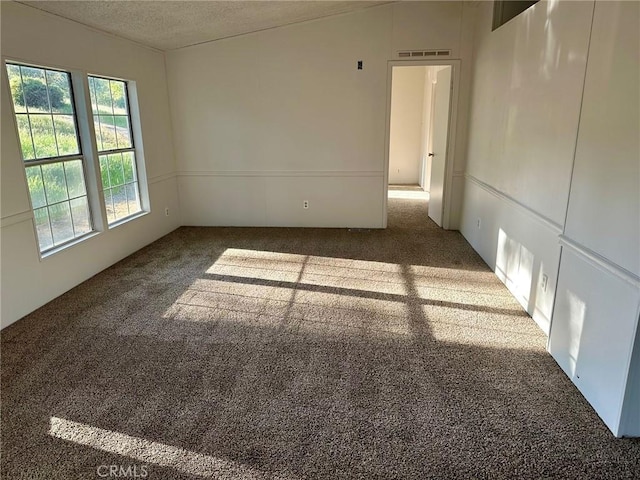 empty room with a textured ceiling and dark colored carpet