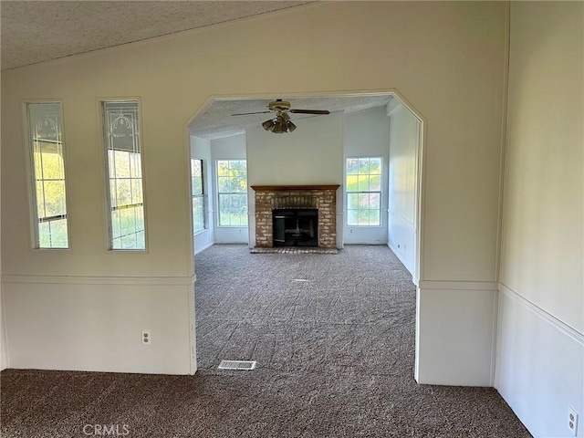 unfurnished living room with ceiling fan, lofted ceiling, a fireplace, and carpet floors