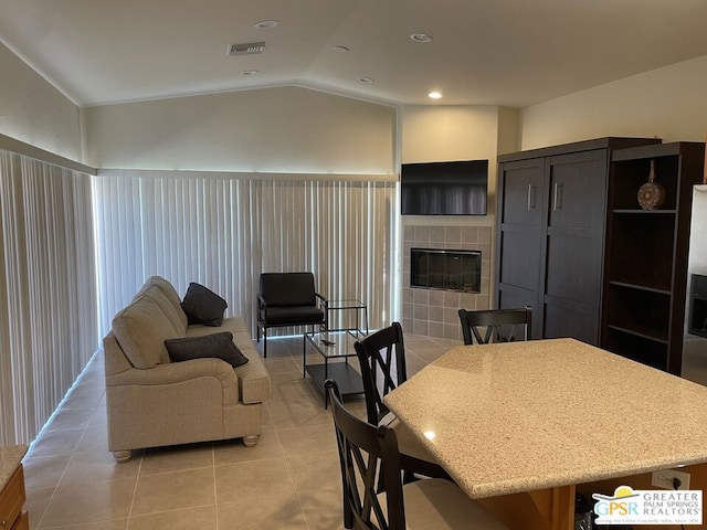 dining area featuring light tile patterned floors, a fireplace, and vaulted ceiling