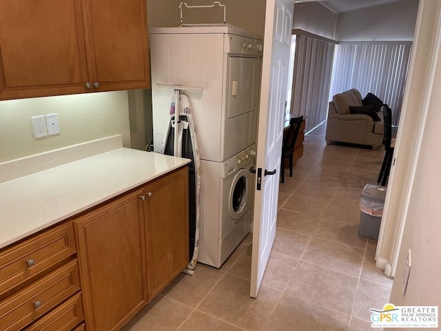 laundry room with cabinets, stacked washing maching and dryer, and light tile patterned floors