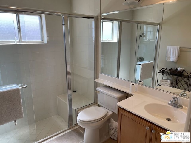 bathroom with tile patterned flooring, vanity, a shower with shower door, and toilet