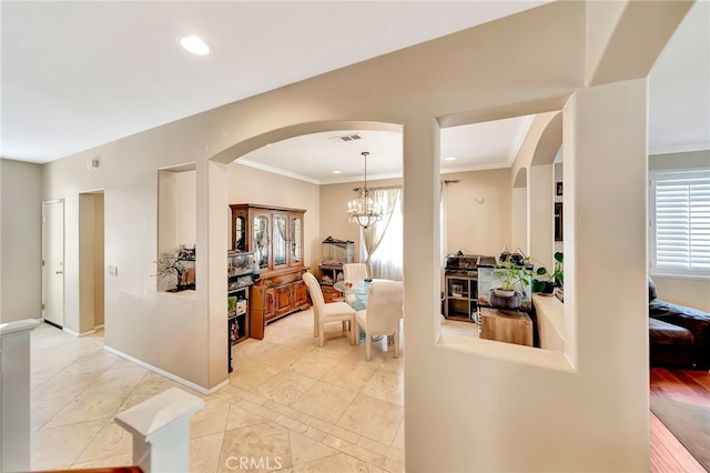 hallway with light tile flooring, a notable chandelier, and crown molding