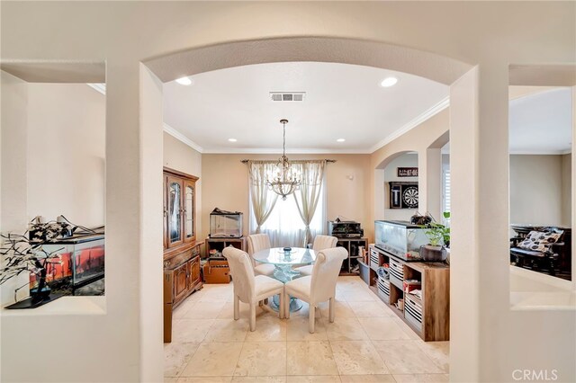 dining space with a notable chandelier, ornamental molding, and light tile floors