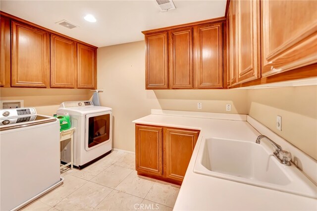 laundry area with cabinets, light tile floors, washer and dryer, and sink