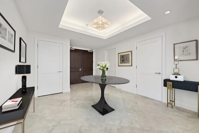 interior space with light tile floors, a raised ceiling, and a notable chandelier