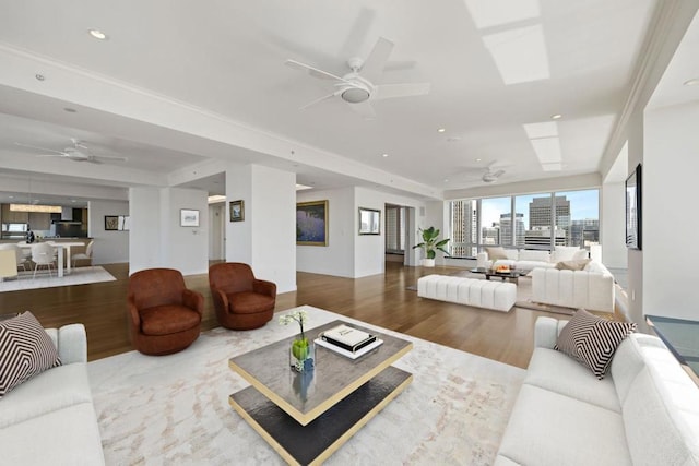 living room with ceiling fan, ornamental molding, a tray ceiling, and hardwood / wood-style flooring