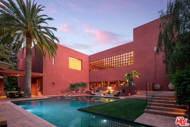 pool at dusk featuring an outdoor living space and a patio