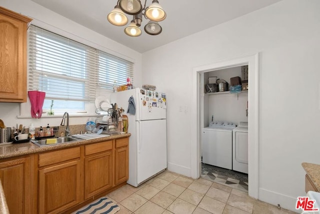 kitchen featuring white fridge, a notable chandelier, sink, light tile floors, and washer and clothes dryer