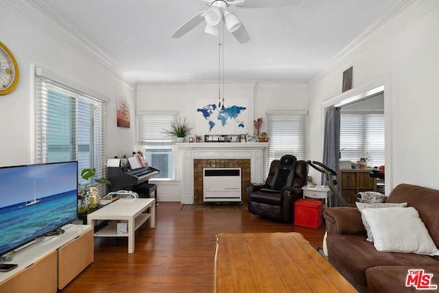 living room featuring ceiling fan, crown molding, dark hardwood / wood-style floors, and a tiled fireplace