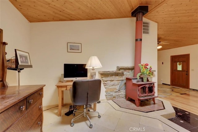interior space with wooden ceiling, ceiling fan, and a wood stove