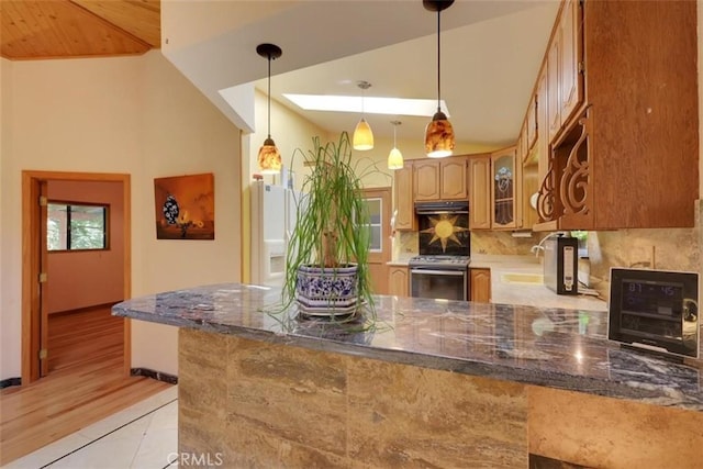 kitchen with glass insert cabinets, stainless steel range oven, a sink, a peninsula, and dark stone counters