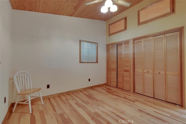 unfurnished bedroom featuring light wood-type flooring, wood ceiling, vaulted ceiling, and two closets