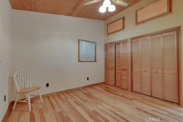 unfurnished bedroom featuring light wood-style flooring, two closets, ceiling fan, and baseboards