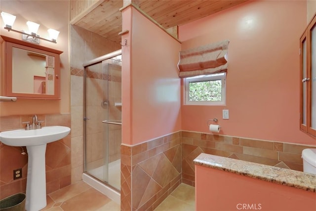 bathroom with tile walls, tile patterned flooring, and a shower with door