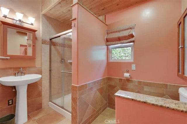 full bath with a shower stall, wooden ceiling, a wainscoted wall, and tile walls