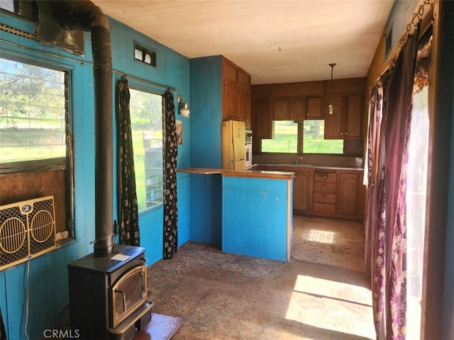 kitchen featuring a wood stove, kitchen peninsula, and white refrigerator