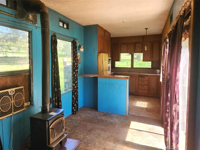 kitchen featuring a wood stove, freestanding refrigerator, carpet, visible vents, and hanging light fixtures