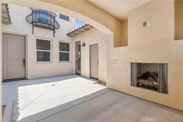 entrance to property with exterior fireplace and a patio