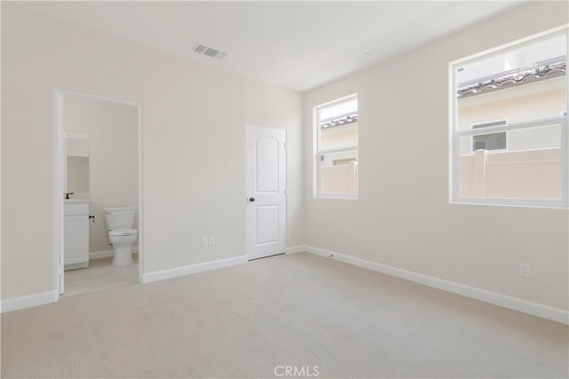 unfurnished bedroom with light carpet and ensuite bath