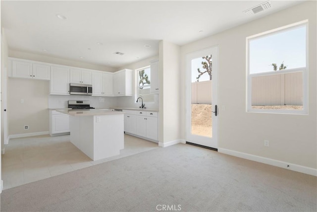 kitchen with a kitchen island, range, and white cabinetry