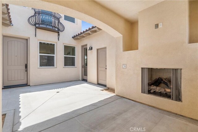 view of exterior entry with exterior fireplace and a patio