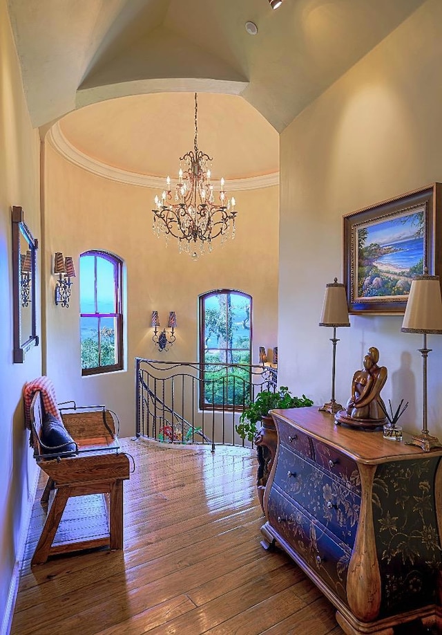 interior space featuring hardwood / wood-style floors, vaulted ceiling, an inviting chandelier, and crown molding