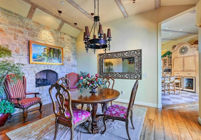 dining space featuring hardwood / wood-style flooring, lofted ceiling with beams, and a notable chandelier