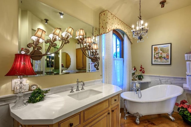 bathroom with a chandelier, hardwood / wood-style floors, vanity, and a bathing tub