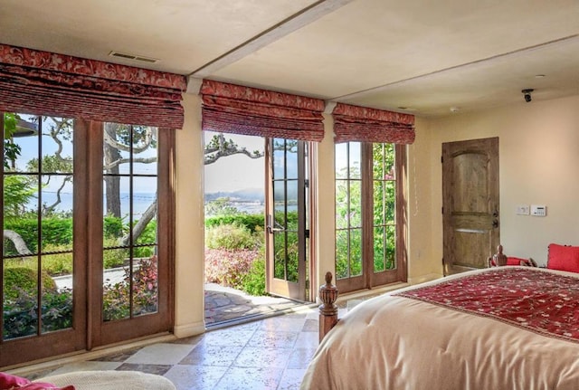 bedroom featuring access to exterior, a water view, french doors, and multiple windows