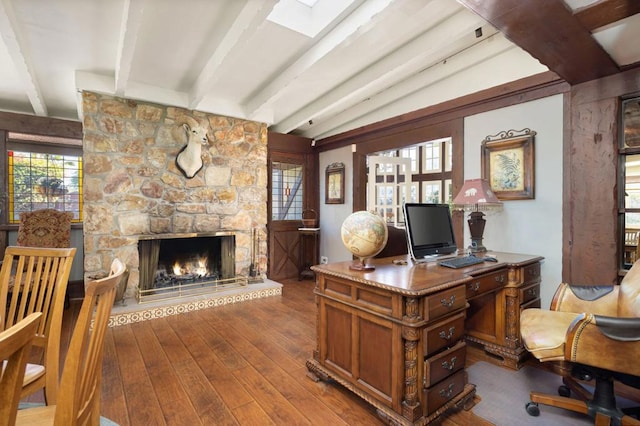 office space with lofted ceiling with skylight, a fireplace, and hardwood / wood-style floors