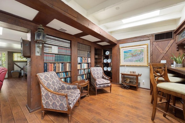 living area featuring beam ceiling and hardwood / wood-style floors