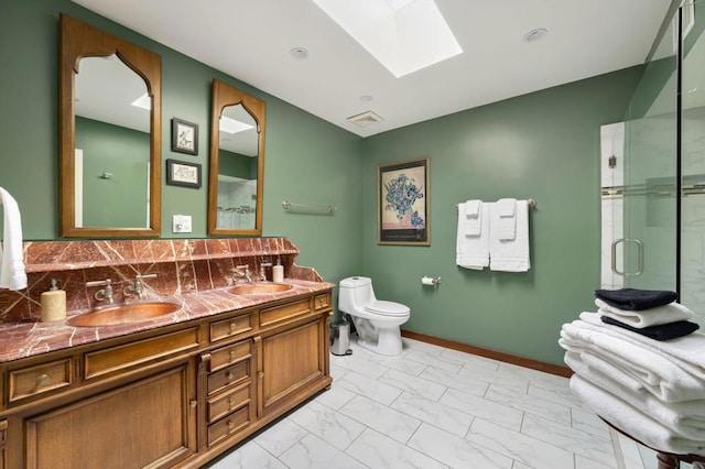 bathroom with vanity, a skylight, toilet, and a shower with door