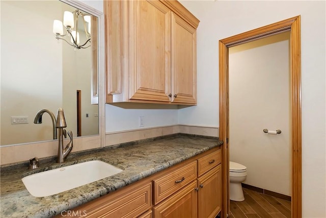 bathroom featuring vanity, toilet, wood-type flooring, and an inviting chandelier