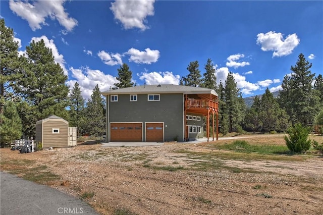 view of side of home featuring a storage shed, a wooden deck, and a garage