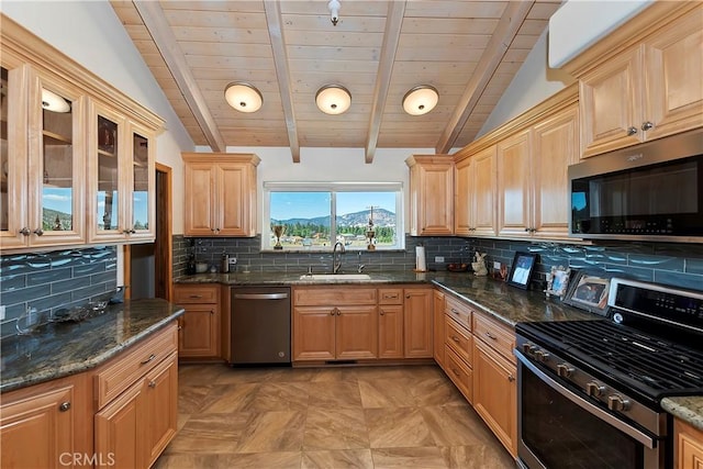 kitchen featuring sink, lofted ceiling with beams, backsplash, dark stone countertops, and appliances with stainless steel finishes