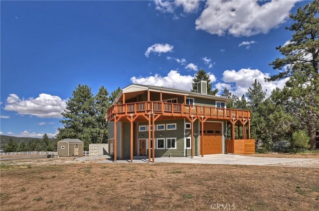 back of property featuring a wooden deck, a patio, a shed, and a garage