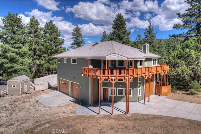 rear view of house with a patio, a garage, a storage shed, and a wooden deck