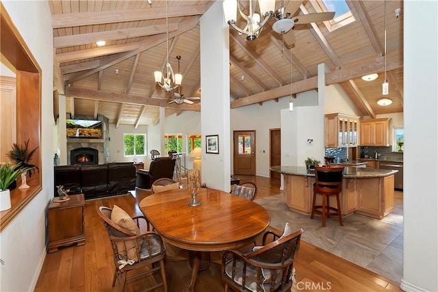 dining area featuring ceiling fan with notable chandelier, beam ceiling, light wood-type flooring, and wood ceiling